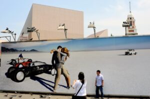 I came across this billboard on my way out of the ferry pier in Tsim Sha Tsui, set against the tight flow of the city yet opening onto an unexpected sense of space. The image offered a distant landscape and a moment of romance that felt far removed from its surroundings. A couple from Mainland China stopped, drawn to the kissing figures. They began taking photos, extending their own memories into the scene. The space on the billboard seemed to absorb them, allowing their brief encounter with the city to take on a different scale.