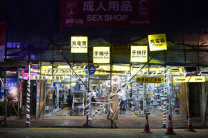 Sex Shop, 2025 - Bright yellow signs lined the storefront, each naming a different device or service, their light spilling onto the pavement. I slowed as the entrance revealed itself through this dense layer of signals. Above it, a large pink sign reading Sex Shop sat apart from what was happening below. The two did not align, holding a tension that refused to settle into a single reading.